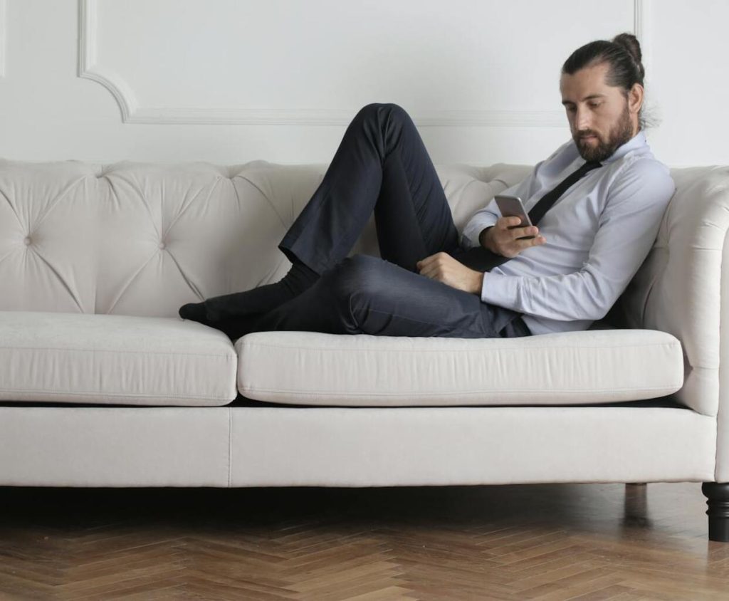 A business person reclines in a sofa enjoying his newly installed wood parquet flooring in herringbone pattern and light oak finish
